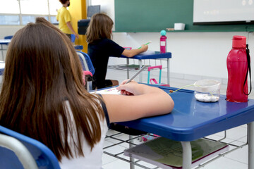 Child studying in a classroom with books and notebooks on the table.