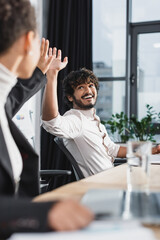 Positive indian businessman giving high five to african american colleague in office.