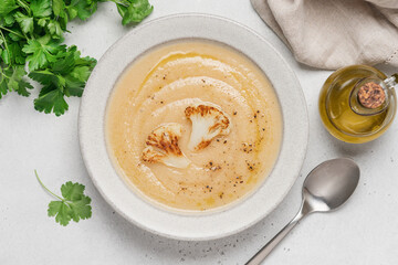 Cauliflower soup in bowl on light background. Vegetable Vegan cream soup with parsley