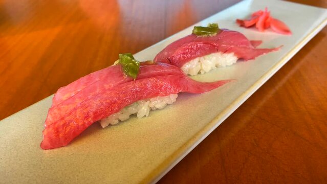 Tasty nigiris with toro tuna and pink pickled ginger, traditional japanese cuisine, rice and fish dish, delicious sushi food in a restaurant, 4K shot