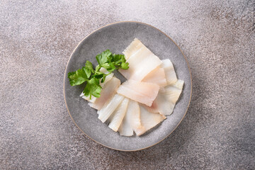 Delicious smoked halibut slices served in white plate isolated on gray background. Top view....