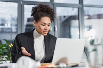 Smiling african american businesswoman having video call on laptop in office.