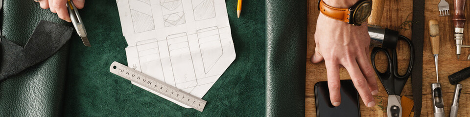 White craftsman working with leather at wooden table in workshop