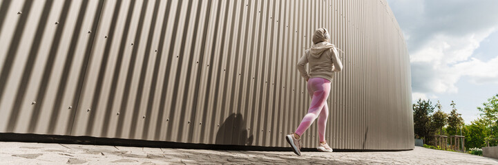 Woman in hijab running while working out at city street