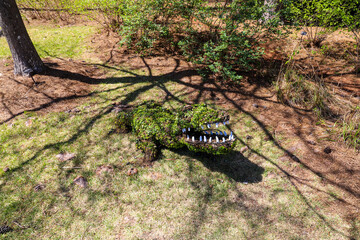a metal alligator covered with lush green leaves surrounded by lush green grass, trees and plants at Callaway Gardens in Pine Mountain Georgia USA