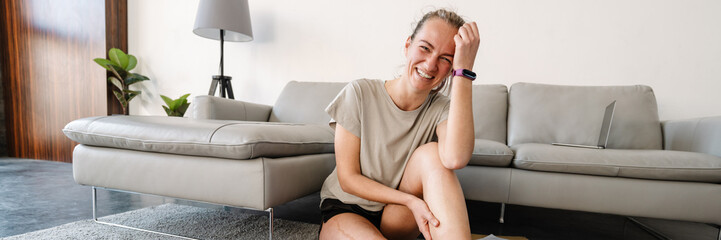 Young white woman smiling while sitting with her prosthesis on floor