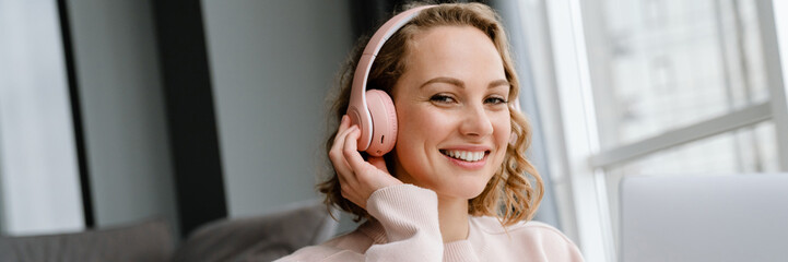 Naklejka premium White woman in headphones using laptop while sitting on floor