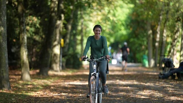 Mother riding bicycle with child in bike back seat outside in nature