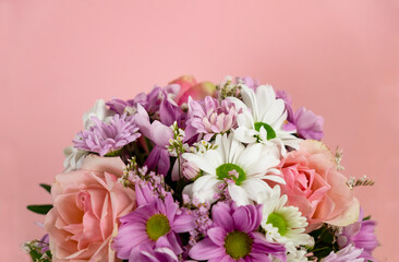 Bouquet of flowers on a pink background. Roses, chrysanthemums of white and lilac color. Place for text