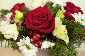 A bouquet of red roses, white chrysanthemums, spruce branches, red berries covered with snow. Winter bouquet