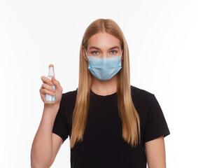 A girl in a medical mask holds a sanitizer in her hand.
