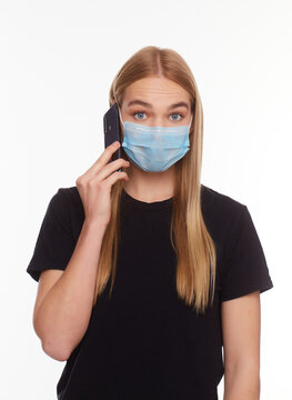 European Girl in a mask uses a telephone. Conceptual photo on the theme of the epidemic.