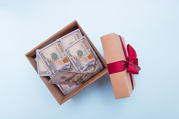 open gift box filled with money on a light blue background.