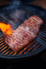 Traditional American barbecue bavette steak as close-up on a charcoal grill with fire