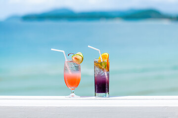 Two tropical fresh iced mocktails on the bar table with sea beach on background. Cocktails on...