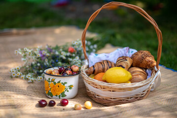 For picnic prepared croissants, cherries, lemon, orange and bouquet of wildflowers.
