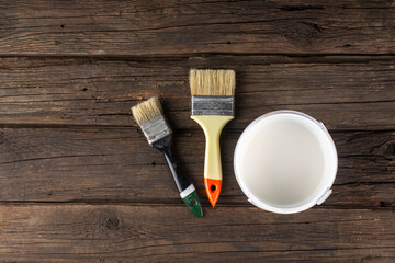 A can of paint and brushes on an old table.
