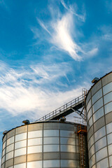 silver silos on agro manufacturing plant for processing drying cleaning and storage of agricultural products, flour, cereals and grain. Large iron barrels of grain. Granary elevator