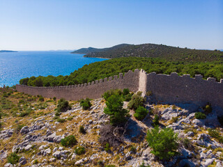 Fototapeta na wymiar Croatia. Summer. Sunny day. Coast of the Adriatic Sea. Ruins of an ancient fortress. Holiday season. Popular tourist spot. Drone. Aerial view