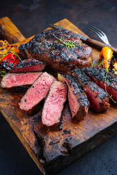 Traditional barbecue dry aged wagyu rib-eye beef steaks served with paprika and zucchini as close-up on an old rustic wooden board
