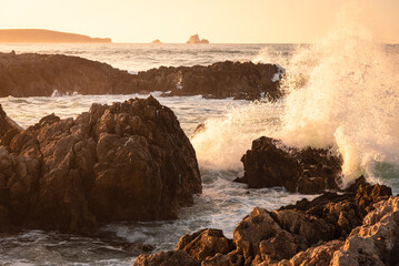 Rough sea waves hit the rocks at the famous surfing beach of Canallave at sunset, Dunas de Liencres Natural Park and Costa Quebrada, Cantabria, Spain