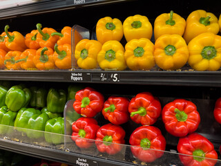 Fresh organic bell pepper selection in produce aisle at grocery store supermarket.