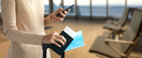 Passenger holds passport with luggage in hand and mobile phone. Immunite passport or certificate for Get vaccinated before flight travel
