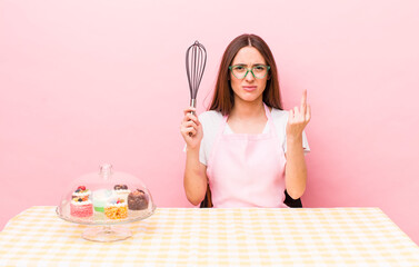 hispanic pretty woman feeling angry, annoyed, rebellious and aggressive. home made cakes concept