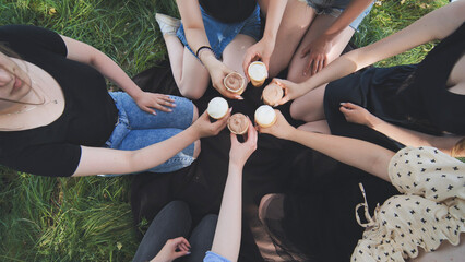 Girls friends join hands with ice cream in waffle cups in a circle.