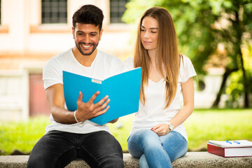Fototapeta premium Two students studying together sitting on a bench outdoor