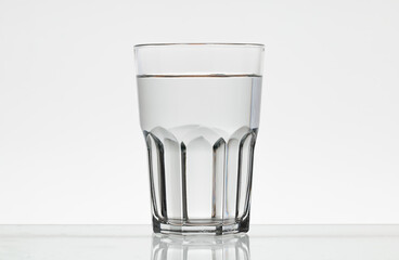Faceted glass of water. Translucent glass on a white background.