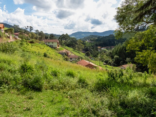 Fototapeta premium Rural landscape in Monte Verde, Minas Gerais, Brazil. Green meadows, houses, trees and mountains