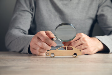 The hand holds a magnifying glass and  toy car