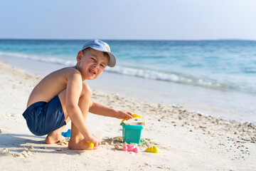Little boy playing with toys on the seaside. Holidays in Maldives