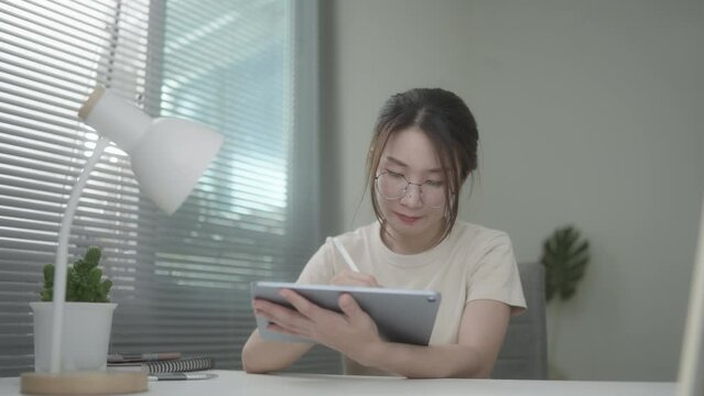 Young Beautiful business woman typing on iPad working at home. Working in room. Morning window light. Soft mood and soft focus.