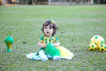 Linda crian&ccedil;a torcedora do brasil num parque fantasiada de verde e amarelo.