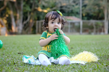 Linda criança torcedora do brasil num parque fantasiada de verde e amarelo.