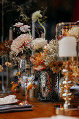 Wedding decor at the restaurant. Beautiful table setting with autumn flowers, orange and burning candles. Autumn wedding concept