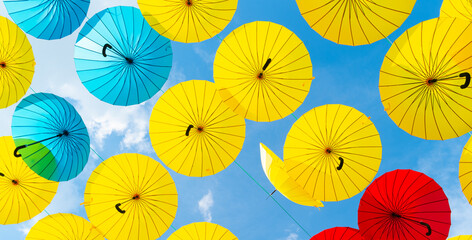 Fototapeta na wymiar Bright color umbrellas hanging on blue sky background bottom-up