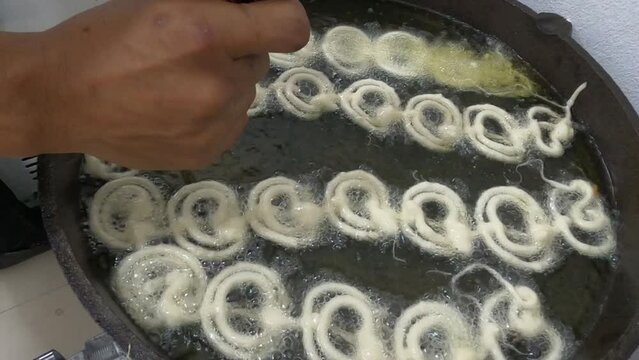 Raw jilapi deep frying 4k video clip.Jilapi making on a hot big pan.Jalebi, also known as jilapi, jilebi, jilipi, zulbia, jerry, mushabak, or zalabia, is a popular Indian sweet snack.