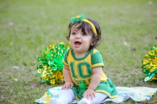 Linda crian&ccedil;a torcedora do brasil num parque fantasiada de verde e amarelo.