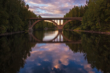 Fototapeta na wymiar old railway Finnish arch bridge on the Janisjoki river in Karelia at sunset