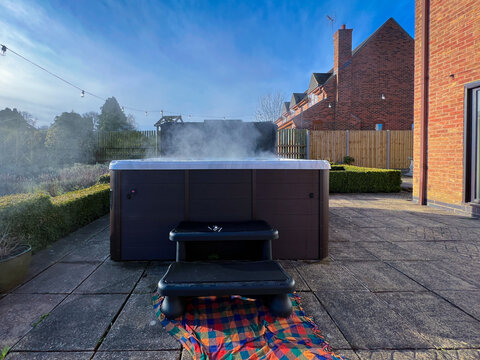 A Steaming Hot Tub On The Outdoor Patio Of A House. 