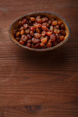 Raisins in a bowl of coconut shell on a wooden table.copy space