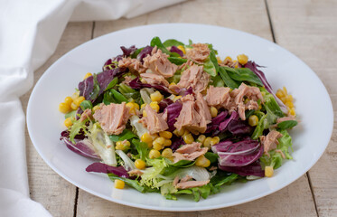 Tuna salad with lettuce, spring onions, brussels sprout, cabbage, arugula, radish and canned tuna. Vitamin salad. Wooden table, close up. Top view