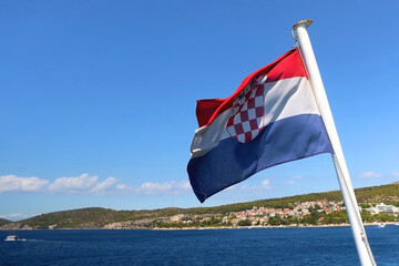 Flag of Croatia on a boat, blowing in the wind. Town Hvar on island Hvar is in the background....