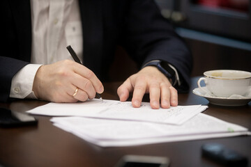 Businessman hand close up writing with pen on the table