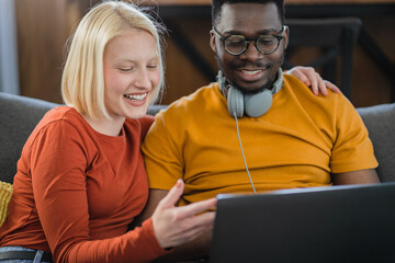 Happy multi-ethnic couple surfing the internet over a laptop computer