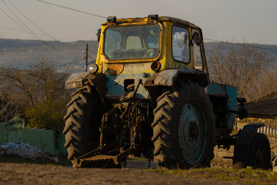 Old yellow tractor. Beautiful misty rural landscape. Agricultural tractor, spring in the countryside. Everyday life in the village. Farming and living in nature. Morning