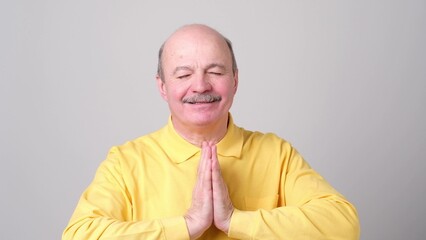 mature man in yellow shirt showing clasped hands,asking for help from God.